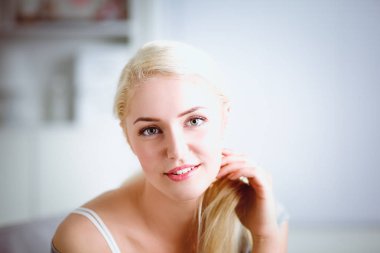 Genç ve güzel bir kadın odasında kanepede oturuyor.