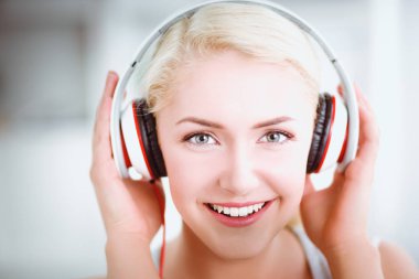 Evdeki genç ve güzel kadın kanepede oturup müzik dinliyor.
