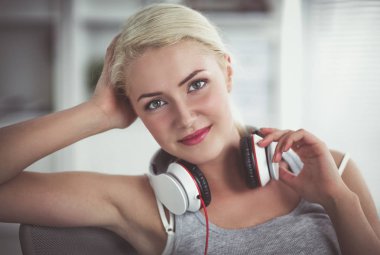 Evdeki genç ve güzel kadın kanepede oturup müzik dinliyor.