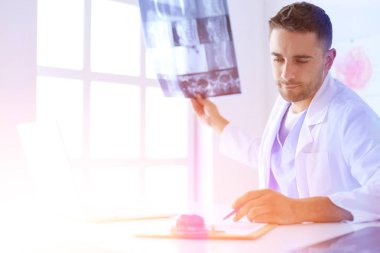 Bilgisayarlı bir erkek doktorun portresi revirde oturuyor.