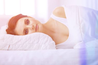 Genç ve güzel bir kadın yatakta yatıyor.