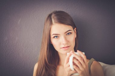 Kanepede oturan ve odada çay içme genç kadın