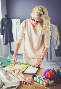 Moda tasarımcısı kadın stüdyoda tasarımları üzerinde çalışıyor.