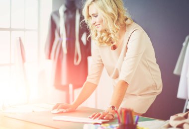 Moda tasarımcısı kadın stüdyoda tasarımları üzerinde çalışıyor.
