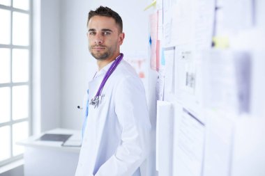 Genç ve kendinden emin erkek doktor portresi tıp ofisinde duruyor.