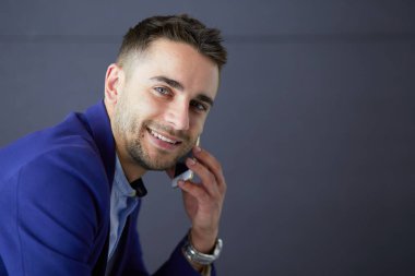 Gri arka planda yalnız oturan genç iş adamı