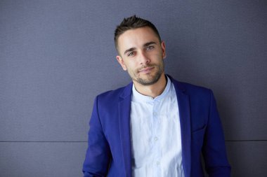 Gri arka planda yalnız oturan genç iş adamı