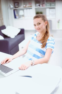 Elinde evrakları olan kadın masanın üstünde oturuyor.