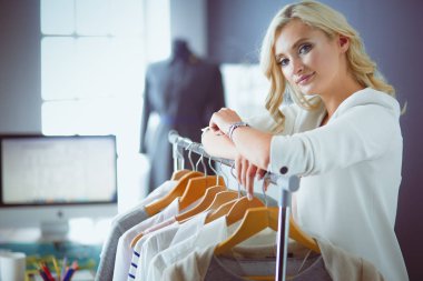 Raf ofiste askıları ile yakınındaki güzel genç stilist