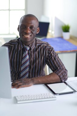 Yakışıklı Afro Amerikalı işadamı Klasik takım elbiseli bir dizüstü bilgisayar kullanarak ve ofiste çalışırken gülümseyen