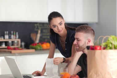 Çift evde mutfak içinde laptop ile onların fatura ödeme