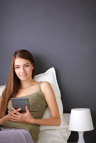 Mujer morena bonita sentada en el suelo con una almohada y mesa de avión — Foto de Stock