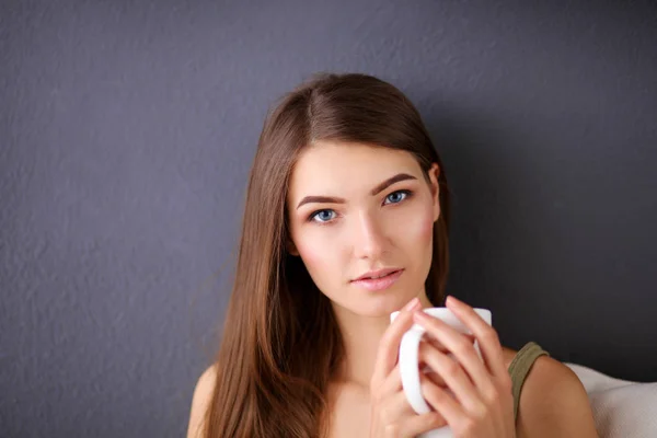 Mujer joven descansando en el sofá y tomando té en la habitación — Foto de Stock