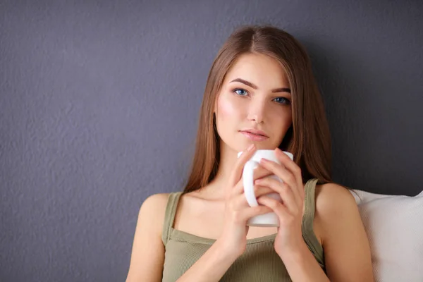 Mujer joven descansando en el sofá y tomando té en la habitación — Foto de Stock