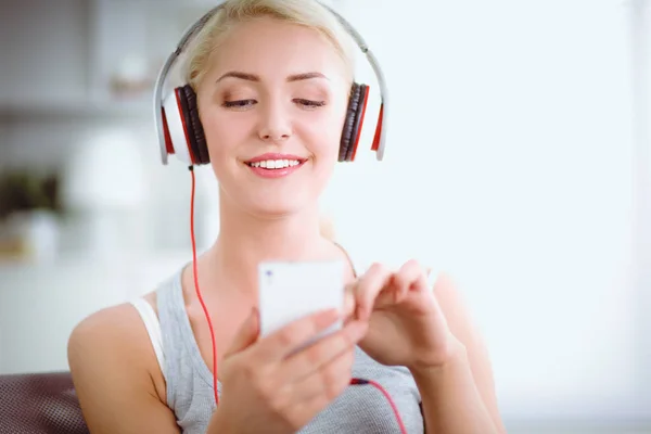 Joven hermosa mujer en casa sentada en el sofá y escuchando música —  Fotos de Stock