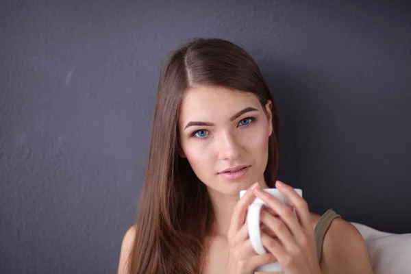 Mujer joven descansando en el sofá y tomando té en la habitación — Foto de Stock