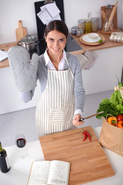 Mujer joven sosteniendo bolsa de la compra de comestibles con verduras. De pie en la cocina — Foto de Stock