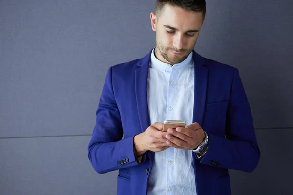 Atraktivní mladý muž s chytrým telefonem na barevném pozadí — Stock fotografie