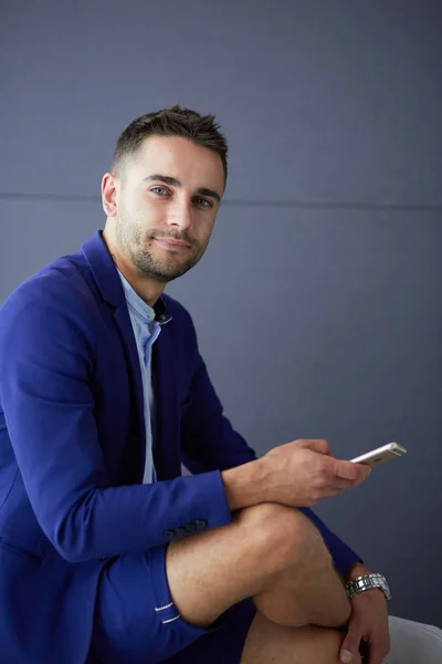 Atractivo joven con teléfono inteligente en el fondo de color —  Fotos de Stock