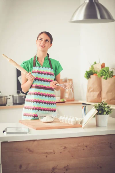 Ung kvinna som håller i matkassen med grönsaker. Stående i köket — Stockfoto