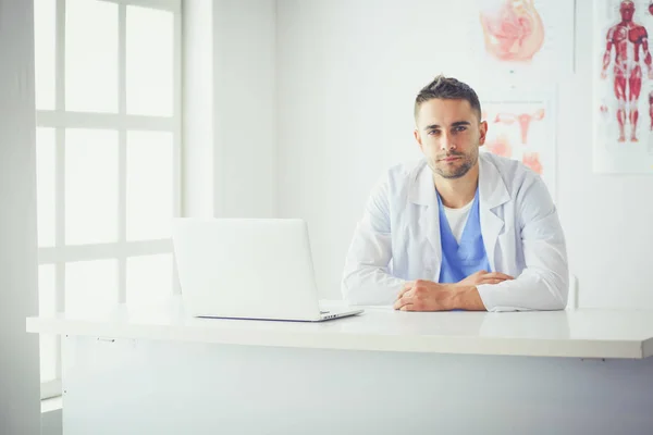 Bilgisayarlı bir erkek doktorun portresi revirde oturuyor. — Stok fotoğraf