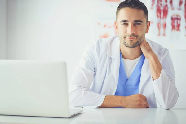 Porträt eines männlichen Arztes mit Laptop am Schreibtisch in der Arztpraxis — Stockfoto