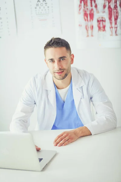 Bilgisayarlı bir erkek doktorun portresi revirde oturuyor. — Stok fotoğraf