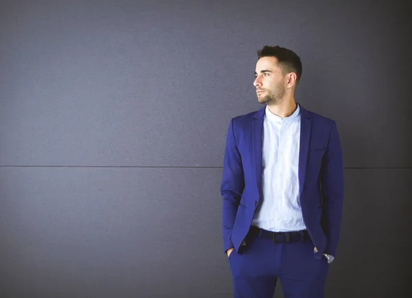 Junger Geschäftsmann steht isoliert auf grauem Hintergrund — Stockfoto