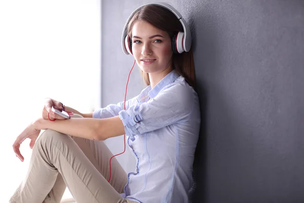 Junges glückliches Mädchen sitzt auf dem Boden und hört Musik — Stockfoto