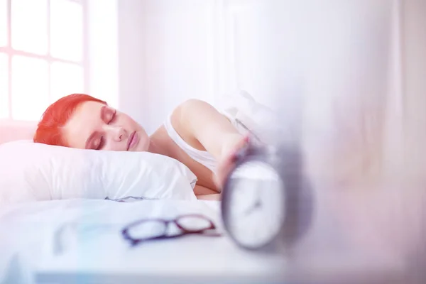 Mulher bonita dormindo enquanto deitada na cama confortavelmente e alegremente no fundo do despertador — Fotografia de Stock