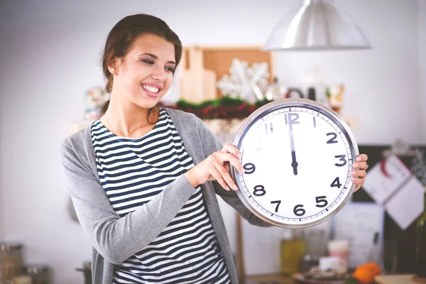 Gelukkig jong vrouw tonen klok in kerst versierd keuken — Stockfoto