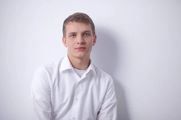 Retrato de un joven sonriendo sentado sobre un fondo gris. Retrato del joven — Foto de Stock