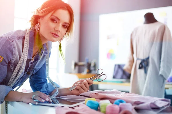 Mulher designer de moda trabalhando com ipad em seus projetos no estúdio — Fotografia de Stock