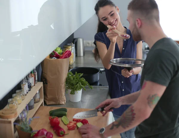 Bir çift evdeki mutfaklarında birlikte yemek pişiriyor.