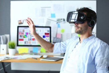Genç erkek yazılım programcısı ofiste üç boyutlu sanal gerçeklik gözlükleriyle yeni bir uygulama test ediyor..
