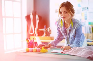 Moda tasarımcısı kadın stüdyoda tasarımları üzerinde çalışıyor.