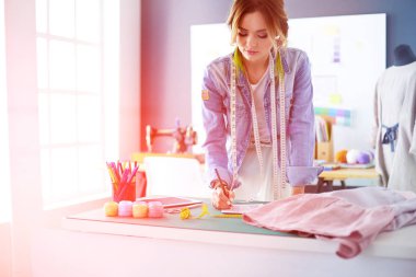 Moda tasarımcısı kadın stüdyoda tasarımları üzerinde çalışıyor.