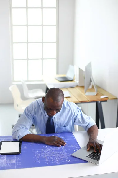 Arquiteto afro-americano trabalhando com computador e plantas no escritório — Fotografia de Stock