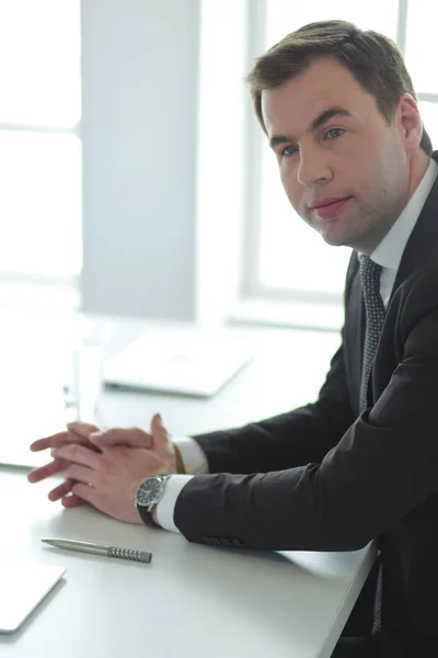 Porträt eines jungen Mannes, der an seinem Schreibtisch im Büro sitzt. — Stockfoto