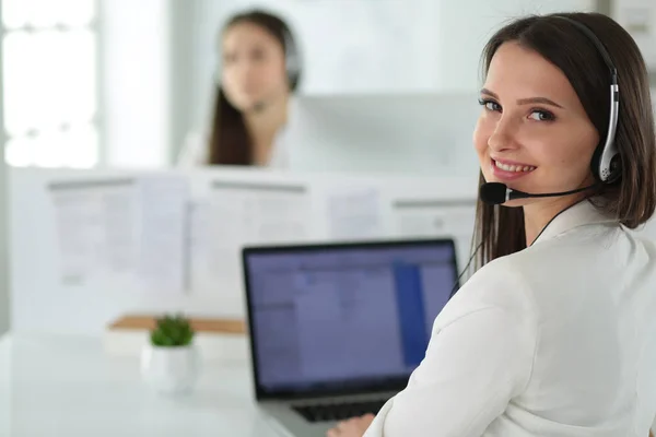 Mujer de negocios sonriente u operador de línea de ayuda con auriculares y computadora en la oficina —  Fotos de Stock