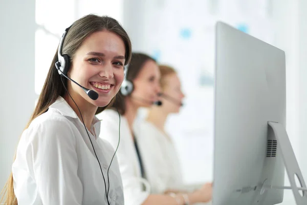 Usmívající se podnikatelka nebo operátorka telefonní linky se sluchátky a počítačem v kanceláři — Stock fotografie