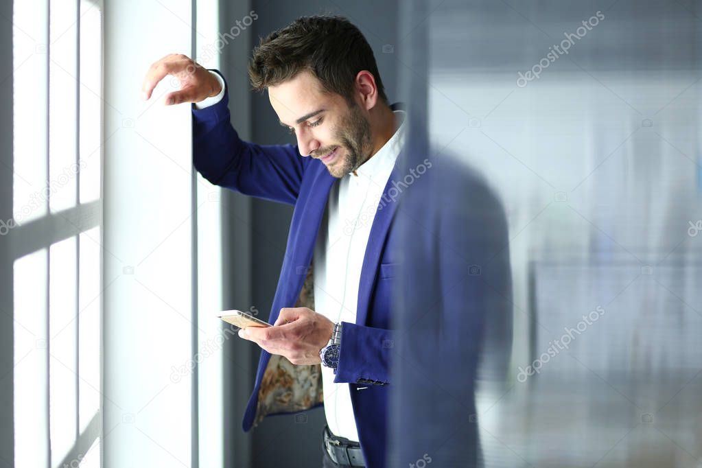 Business man in suit talking on phone and looking away near the window.