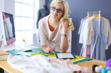 Moda tasarımcısı kadın stüdyoda tasarımları üzerinde çalışıyor.