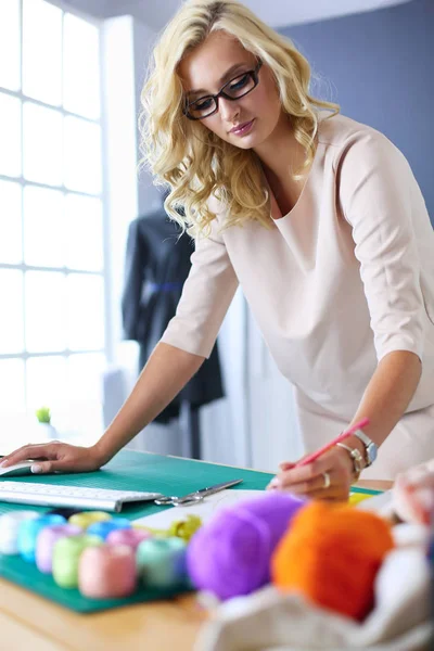 Moda tasarımcısı kadın stüdyoda tasarımları üzerinde çalışıyor.