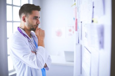 Genç ve kendinden emin erkek doktor portresi tıp ofisinde duruyor.