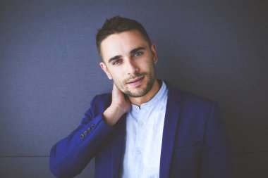 Gri arka planda yalnız oturan genç iş adamı