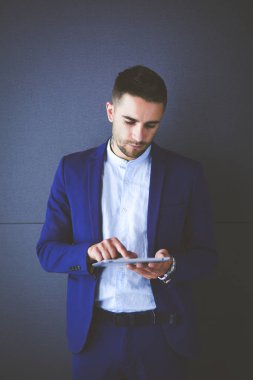 Gri arka planda yalnız oturan genç iş adamı