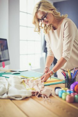 Moda tasarımcısı kadın stüdyoda tasarımları üzerinde çalışıyor.