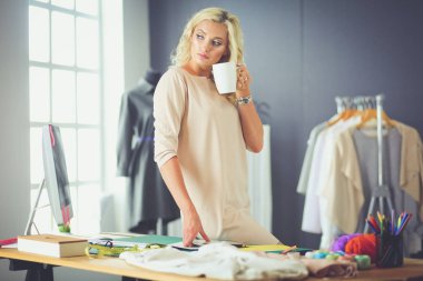 Moda tasarımcısı kadın stüdyoda tasarımları üzerinde çalışıyor.