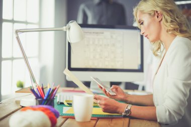 Moda tasarımcısı kadın stüdyoda tasarımları üzerinde çalışıyor.